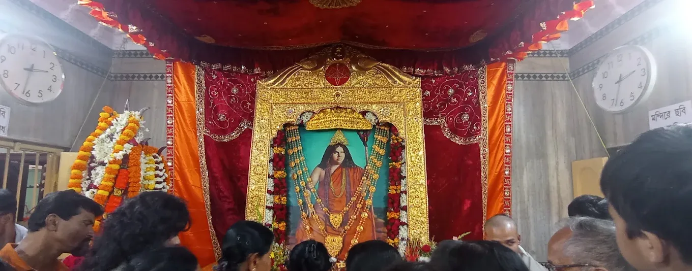 Festivals & Observances: Devotees gathered before a garlanded portrait on a decorated stage during an observance