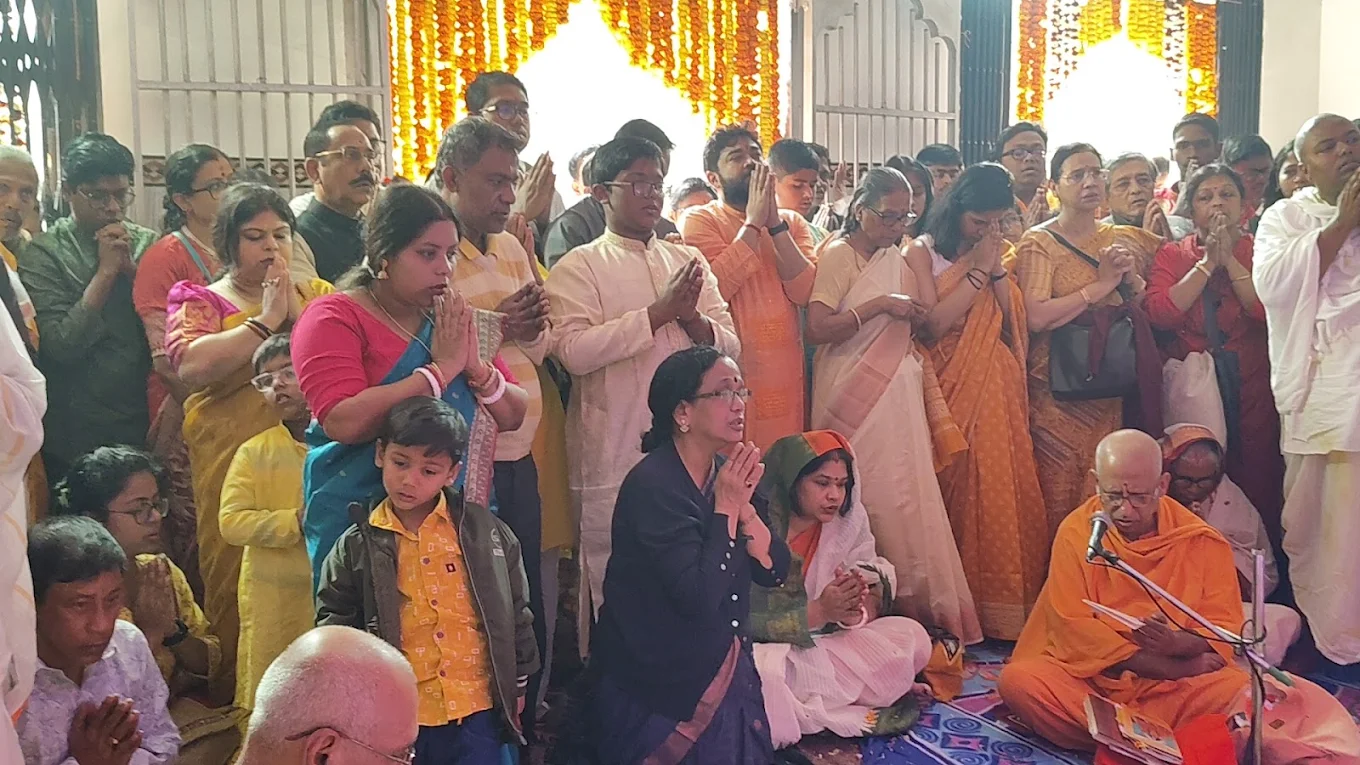Devotees standing with folded hands as a monk conducts a ritual