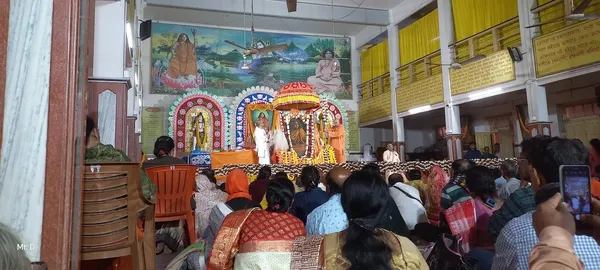 Community: An audience seated in the hall before a decorated stage during a programme