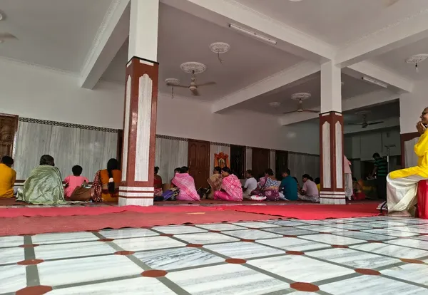 Community: Devotees seated on the floor of the prayer hall reading scripture together