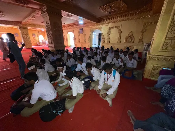 Education: Schoolchildren in uniform seated on the floor of the hall for a students programme