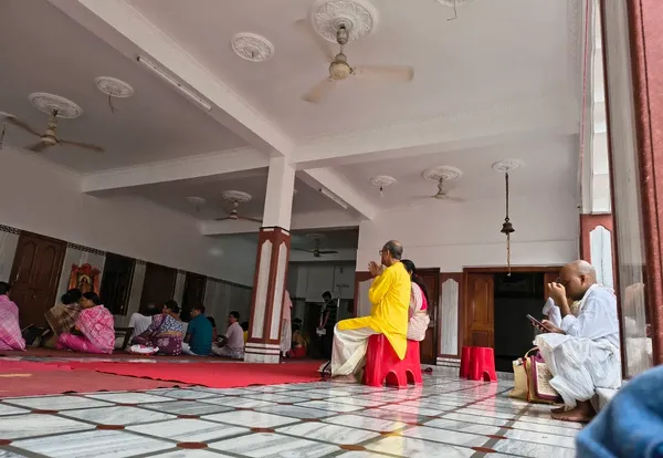 Community: The prayer hall during a service, with a monk standing and devotees seated on the floor